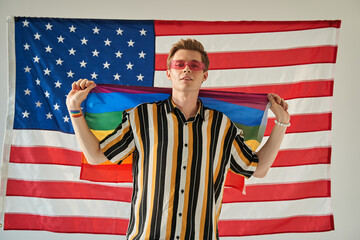 Man showing lgtbi flag while posing with USA flag at the background