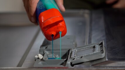 man's hand  putting liquid dish soap in the dishwasher - house cleaning and single father 