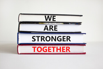 Stronger together symbol. Books with words 'we are stronger together'. Beautiful white background. Businessman hand. Copy space. Business, motivational and we are stronger together concept.