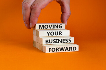 Moving your business forward symbol. Concept words 'Moving your business forward' on wooden blocks on a beautiful orange background. Businessman hand. Business, motivational, success concept.