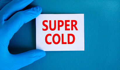 Super cold symbol. Words Super cold on white card. Doctor hand in blue glove. Beautiful blue background. Medical, Covid-19 and super cold concept.
