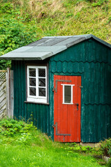 Fototapeta na wymiar Grünes Gartenhäuschen mit roter Tür