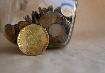 bitcoin coin. a glass piggy bank. lots of coins. finance. brown background