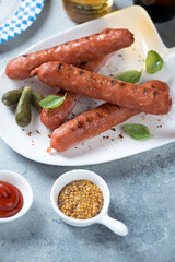 Close-up of grilled german bratwurst sausages with dips over light-blue stone surface, vertical shot