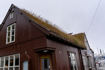 View of the beautiful city of Torshavan in the Faroe Islands and its clausal colorful houses, red building Goverment with grass on the roof , and marina.