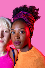 Portrait of two diverse women friends posing isolated background standing for equality against...