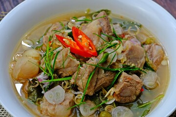 Cartilage pork curry seasoned with fermented shrimp paste chili sauce (Run Juan Curry, Gaaeng ranjuaan) in white bowl on wooden table. Authentic royal Thai cuisine.