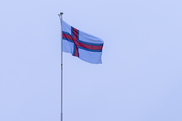View of the beautiful Faroe Islands Flag in the city of Torshavan in the Governments red building  with grass on the roof