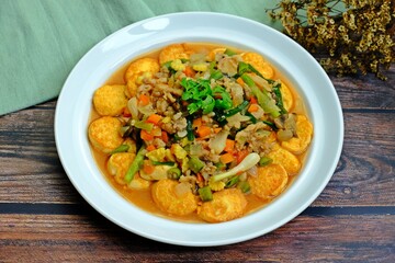 Deep fried tofu with gravy sauce (Tao Hoo Song Kreung) in white plate on wooden table, Healthy dish.