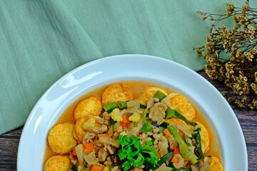 Deep fried tofu with gravy sauce (Tao Hoo Song Kreung) in white plate on wooden table, Healthy dish.