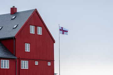 View of the beautiful Faroe Islands Flag in the city of Torshavan in the Governments red building  with grass on the roof