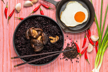 Healthy food black rice in bowl with mushroom fried egg have garlic chili herb on table