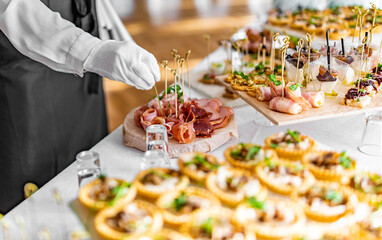 woman hands of a waiter prepare food for a buffet table in a restaurant