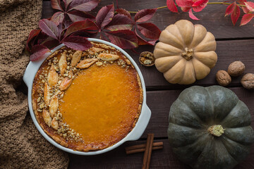 homemade pumpkin pie with walnuts, beautifully decorated with dough leaves, dark wooden background, top view from above