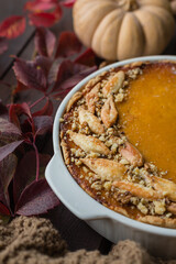 homemade pumpkin pie with walnuts, beautifully decorated with dough leaves, dark wooden background, soft selective focus