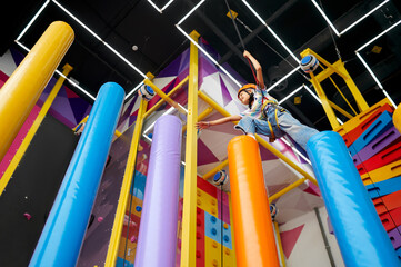 Little girl in helmet on climbing area, climber