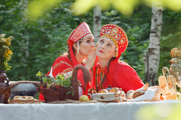 Girl, young russian woman in Russian national sundress, sarafan, and a kokoshnik whispering, emotions, wonder, russian teatime, selective focus