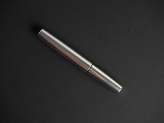 close-up of a closed mascara of silver color on a black background. The concept of cosmetics for women. top view, flat lay