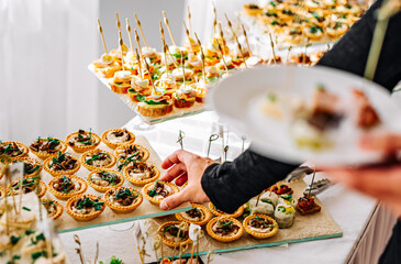 man hands take a snack and put it on plate. buffet in a restaurant