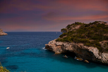 Turquoise beach cliffs with orange sunrise or sunset skies