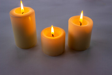 Fototapeta na wymiar Three white candles burning on gray gradient background. Top view. 