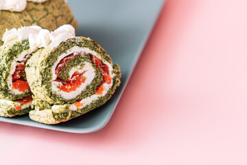 Sliced roll with spinach and red fish in plate on pink background