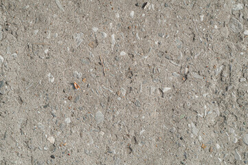 The texture of the old concrete pavement. Inclusions of small stones in the concrete floor.