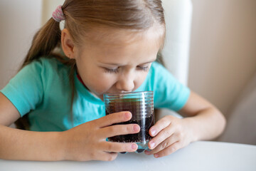 Happy little girl drinking soda from glass