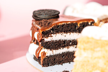 Chocolate piece of cake with cookies on top on pink background
