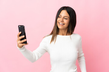 Fototapeta premium Caucasian girl isolated on pink background making a selfie