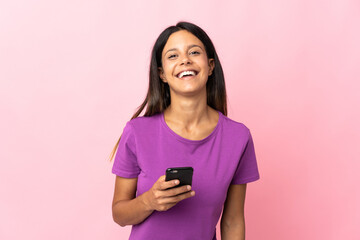 Caucasian girl isolated on pink background using mobile phone