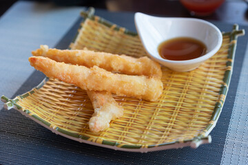 Shrimps tempura with soy sauce on yellow bamboo plate. Seafood tempura dish of traditional asian cuisine