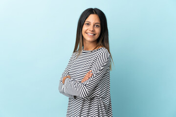 Caucasian girl isolated on blue background with arms crossed and looking forward