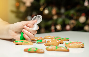 Unrecognizable woman decorating gingerbread in the kitchen