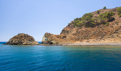 Fototapeta na wymiar Rocky island beach with turquoise calm water and clear blue sky