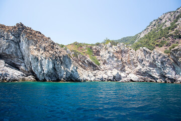 Rocky island seashore with turquoise calm water and clear blue sky