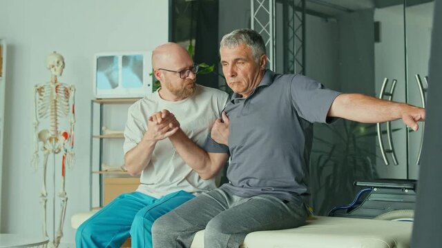 A Sick Man With a Brain Stroke Undergoes a Rehabilitation Program with a Physiotherapist in a Modern Clinic. Incapacity for Work, Limited Movement, Paralysis. Elderly Health Support Concept.