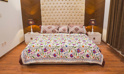 Contemporary Bed with purple and green flower bedsheet and huge white head board and brown background