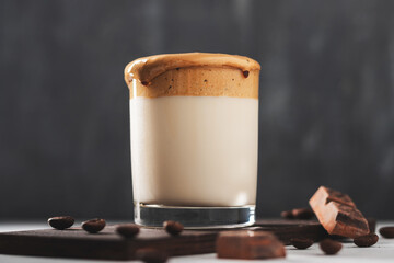 Whipped Dalgona coffee drink in a glass with milk, dark background