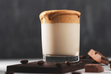 Whipped Dalgona coffee drink in a glass with milk, dark background