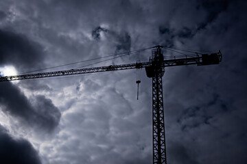 Duży dźwig budowlany ( żuraw) na tle ciemnego, pochmurnego nieba. A large construction crane against the background of a dark, cloudy sky. © Grzegorz