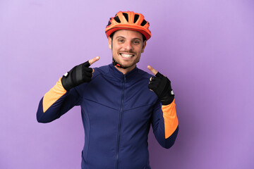 Young Brazilian cyclist man isolated on purple background giving a thumbs up gesture