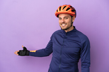 Young Brazilian cyclist man isolated on purple background extending hands to the side for inviting to come