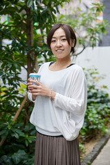 コーヒーの紙コップを持ったアジア人女性