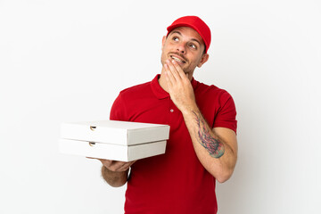 pizza delivery man with work uniform picking up pizza boxes over isolated  white wall looking up...