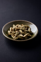 Green Cardamom Seeds on dark paper background. Close up. Copy space. 