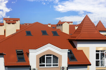 view of the roofs of houses and dormers from the skylight, against the background of the blue sky.