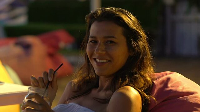 Portrait of happy, pretty girl drinking cocktail in cafe on beach
