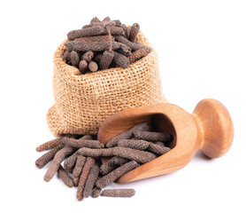 Long pepper in small burlap sack and scoop, isolated on white background. Heap of pippali or piper...