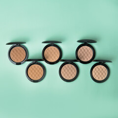 Multiple blush and compact face powders on a delicate mint green background. Pastel trendy colors matte foundation